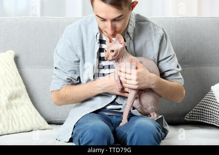 Young handsome man sitting with cat on couch at home Stock Photo