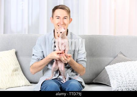 Young handsome man sitting with cat on couch at home Stock Photo