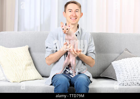 Young handsome man sitting with cat on couch at home Stock Photo