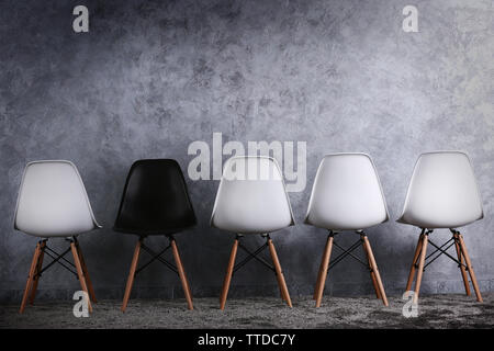Stylish conception with white and black chairs on grey background Stock Photo