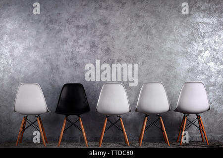 Stylish conception with white and black chairs on grey background Stock Photo