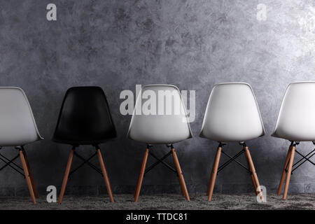 Stylish conception with white and black chairs on grey background Stock Photo