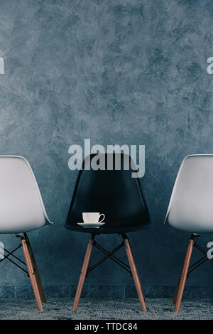 Stylish conception with white and black chairs on grey background Stock Photo