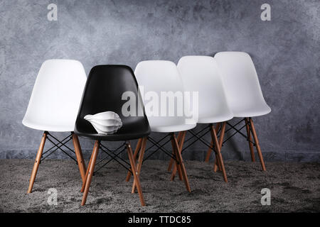 Stylish conception with white and black chairs on grey background Stock Photo