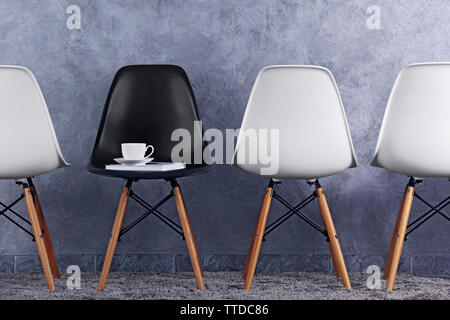 Stylish conception with white and black chairs on grey background Stock Photo