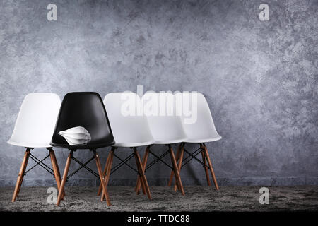 Stylish conception with white and black chairs on grey background Stock Photo