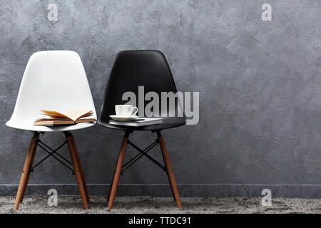 Stylish conception with white and black chairs on grey background Stock Photo