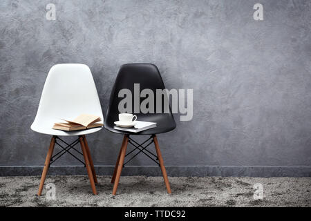 Stylish conception with white and black chairs on grey background Stock Photo