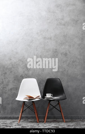 Stylish conception with white and black chairs on grey background Stock Photo
