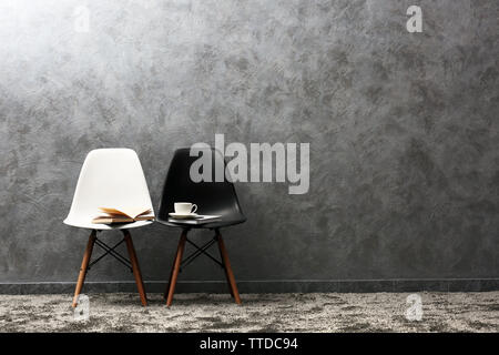 Stylish conception with white and black chairs on grey background Stock Photo