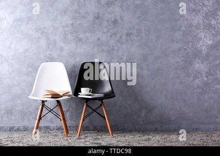 Stylish conception with white and black chairs on grey background Stock Photo