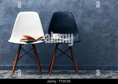 Stylish conception with white and black chairs on grey background Stock Photo