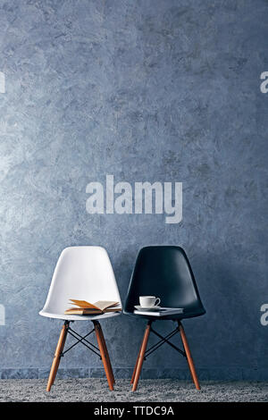 Stylish conception with white and black chairs on grey background Stock Photo