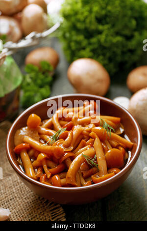 Delicious marinated mushrooms in bowl on wooden background Stock Photo