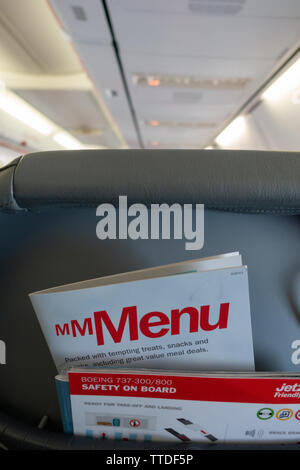 Back of the passenger seat on a  Boeing 737 showing magazine rack with flight menu and safety card Stock Photo