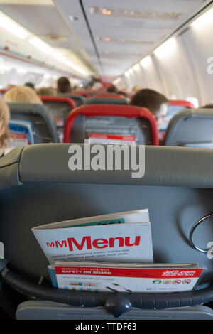 Back of the passenger seat on a  Boeing 737 showing magazine rack with flight menu and safety card