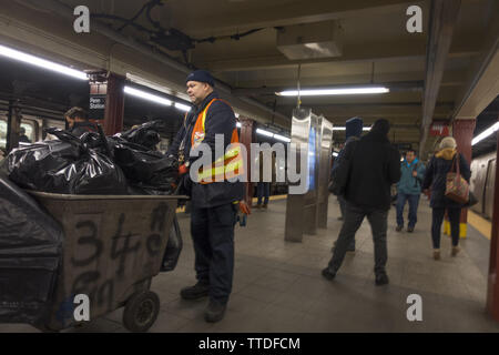 MTA custodial worker emptying garbage on the  34th Street subway train platform at Penn Station in Manhattan. Stock Photo