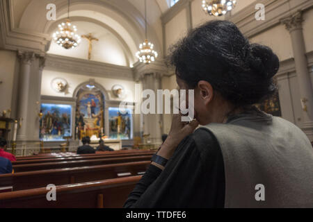 Woman deep in thought at a Catholic Church in midtown Manhattan. Stock Photo