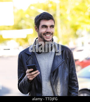Young man listening to music and walking along the street Stock Photo