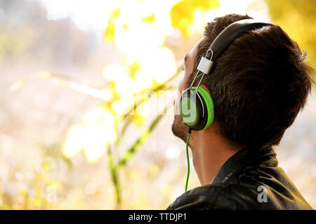 Young man sitting under the tree and listening to music Stock Photo