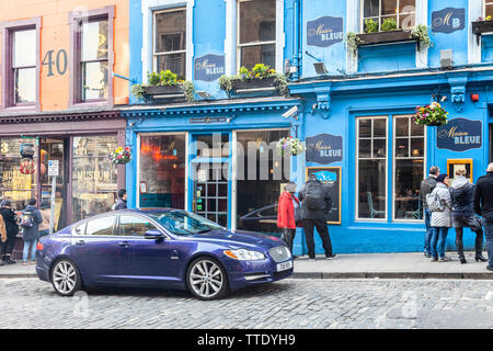 A dark blue Jaguar car parked outside Maison Bleue, a French restaurant in Victoria Street, Edinburgh, next to Museum Context, a Harry Potter shop. Stock Photo