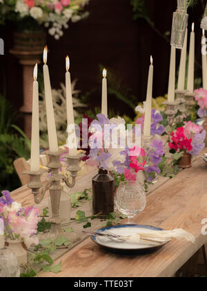 garden table set with candles and sweet pea flowers Stock Photo