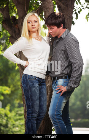 Happy young fashion couple in city park Stylish trendy man and woman in long sleeve shirts and blue jeans Stock Photo