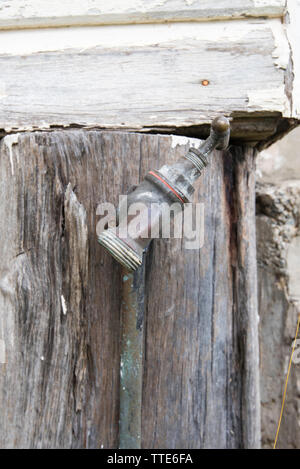An old brass outdoor tap or faucet mounted on a timber post at the corner of an old country church in Krambach New South Wales, Australia Stock Photo