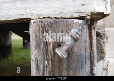 An old brass outdoor tap or faucet mounted on a timber post at the corner of an old country church in Krambach New South Wales, Australia Stock Photo