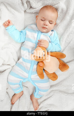 Adorable baby sleeping with teddy bears on sofa in the room, close up Stock Photo