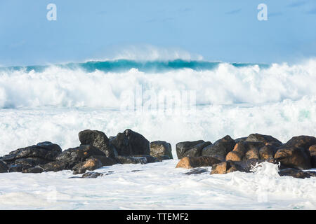 Giant blue waves crashing into large rocks near the Banzai Pipeline on the North Shore of Oahu, Hawaii. Stock Photo