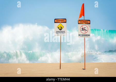 Warning signs indicating no swimming allowed due to huge waves and dangerous shorebreak near the Banzai Pipeline on the North Shore of Oahu, Hawaii. Stock Photo