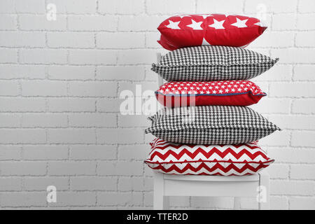 Colorful pillows on chair, on white bricks wall background Stock Photo