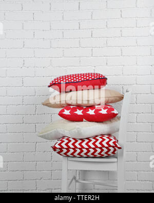 Colorful pillows on chair, on white bricks wall background Stock Photo