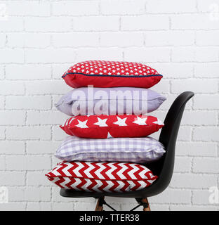 Colorful pillows on chair, on white bricks wall background Stock Photo