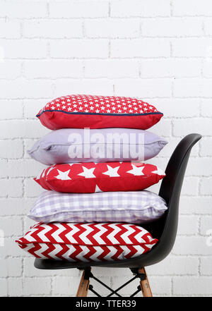 Colorful pillows on chair, on white bricks wall background Stock Photo