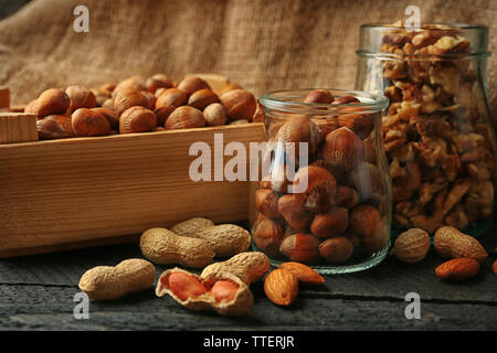 Mix of nuts in the glass jars and wooden box, on the table Stock Photo