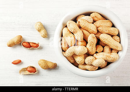 Peanuts in the bowl on white wooden background Stock Photo