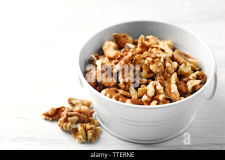 Walnut kernels in the metal bucket on white wooden background Stock Photo