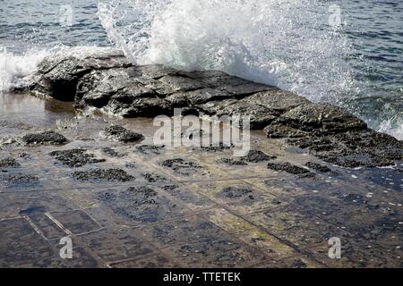 Tessellated pavement with ocean wave crashing over rocks in Tasmania Stock Photo