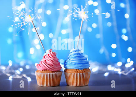 Two cupcakes with sparklers on a glitter background Stock Photo