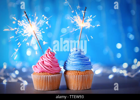 Two cupcakes with sparklers on a glitter background Stock Photo