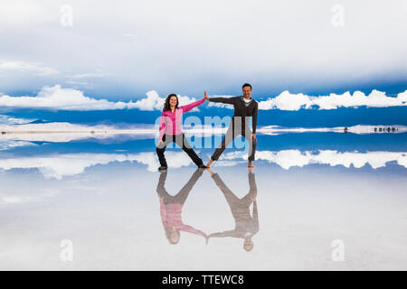 Uyuni, Bolivia- Dec 31, 2018: Man and woman make figures with their bodies on the lake Salar de Uyuni, Bolivia. America Stock Photo