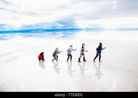 Uyuni, Bolivia- Dec 31, 2018: Group of people make evolution figure with their bodies on the lake Salar de Uyuni, Bolivia. America Stock Photo