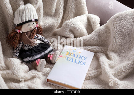Rag doll with fairy tales book on  bedspread. Childhood concept Stock Photo
