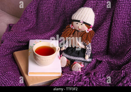 Rag doll with fairy tales books and cup of tea on bedspread. Childhood concept Stock Photo