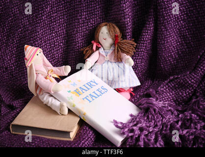 Rag dolls with fairy tales books on bedspread. Childhood concept Stock Photo