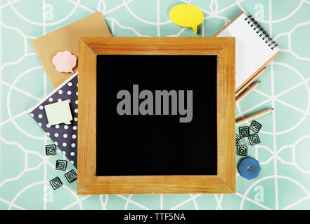 Small school blackboard with stationery on patterned background