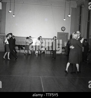 1950s, historical, men and women dancing together at an evening ballroom dancing class under the watchful eye of a male dance teacher, England, UK. Learning ballroom dance was a pooular recreational activity in this era as well as being a competitve pursuit. Stock Photo