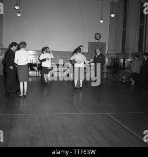 1950s, historical, men and women dancing together at an evening ballroom dancing class under the watchful eye of a male dance teacher, England, UK. Learning ballroom dance was a pooular recreational activity in this era as well as being a competitve pursuit. Stock Photo